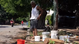 cubano cargando cubetas de agua
